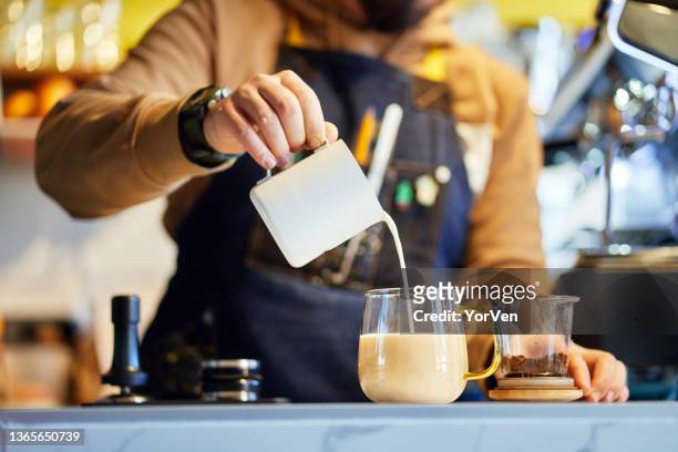fresh milk poured into cup of tea by man hand - milk tea cup stock pictures, royalty-free photos & images