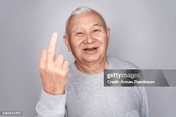 senior man at the wall making middle finger gesture - middle finger funny 個照片及圖片檔