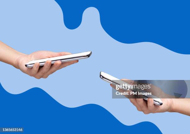 two woman's hands holding smart phones - phone hand stock-fotos und bilder