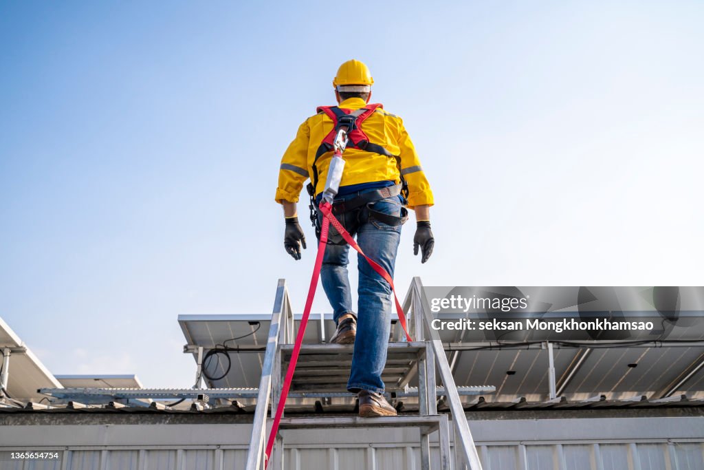 Construction worker wearing safety harness and safety line working at high place