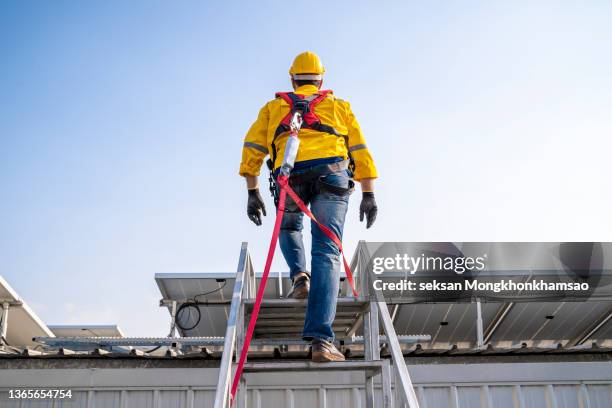 construction worker wearing safety harness and safety line working at high place - safety harness - fotografias e filmes do acervo