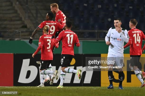 Stefan Lainer of Gladbach looks on whilst Sebastian Kerk of Hannover celebrates the 2nd team goal with his team mates during the DFB Cup round of...