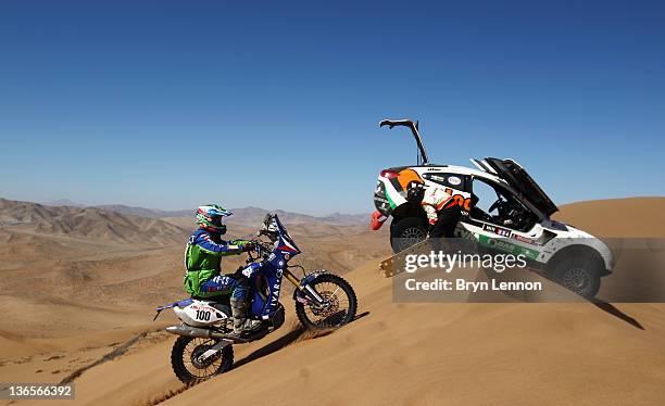 Erik van Loon of The Netherlands and co-driver Harmen Scholtalbers try to free their Mitsubishi after getting stuck on a sand dune as Jan Vesely of...