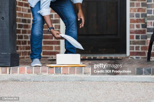 unrecognizable man picks up packages on doorstep - shipping box stock pictures, royalty-free photos & images