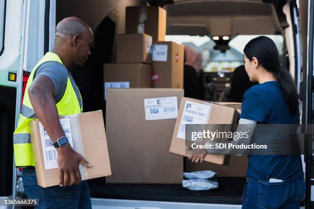 two delivery people unloading packages from van - delivery van stock pictures, royalty-free photos & images