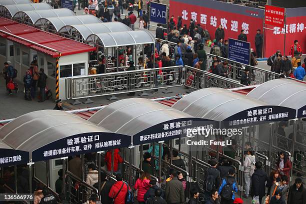 Chinese people walk with their luggage at the entrance of the check-in kiosks for real-name tickets at Beijing West Railway Station on January 8,...