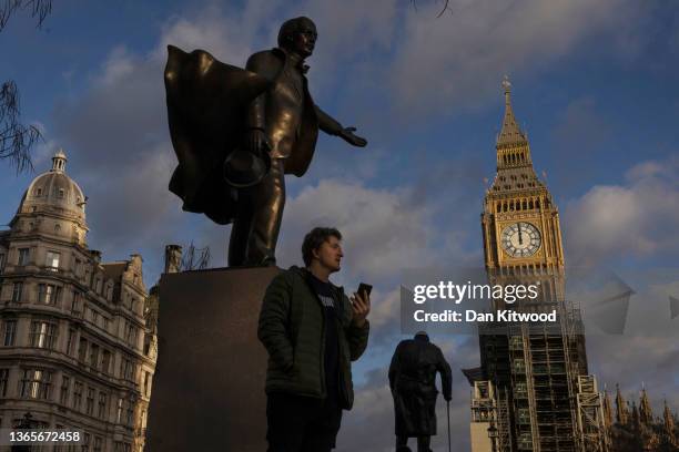 Man speaks on his phone next to statues of former Prime Minister’s, David Lloyd George and Winston Churchill in Parliament Square on January 19, 2022...