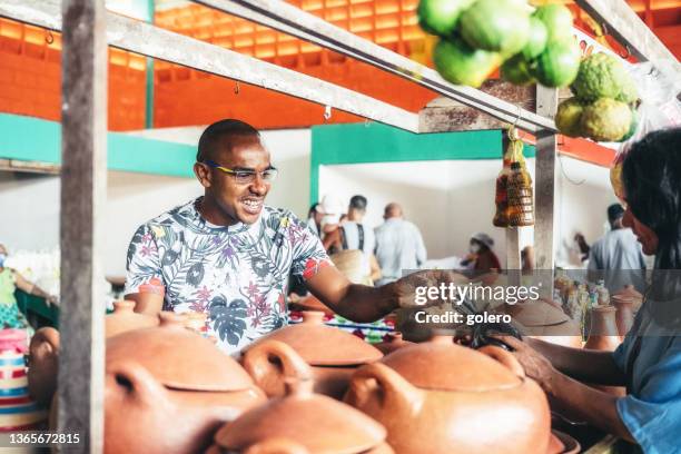 lächelnder junger marktverkäufer am töpferstand mit weiblicher kundin - kunsthandwerk stock-fotos und bilder