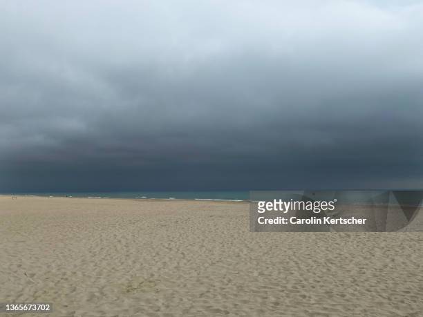 sandy beach with thunderstorm rolling and dark clouds - summer storm stock pictures, royalty-free photos & images