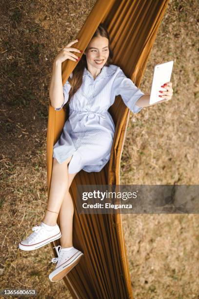 woman resting in hammock and reading magazine on digital tablet - nature magazine 個照片及圖片檔