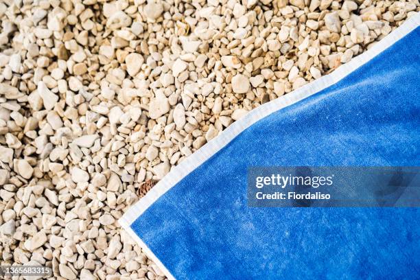 blue towel lying on the coastal sea pebbles - strandhanddoek stockfoto's en -beelden