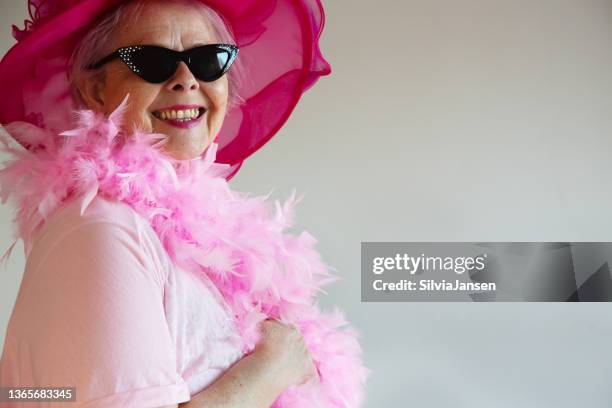 happy senior woman wearing pink feather boa and hat - boa bildbanksfoton och bilder