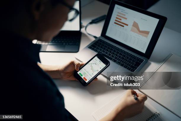 mid adult man checking financial information on a smart phone while doing his bookkeeping - early retirement stockfoto's en -beelden