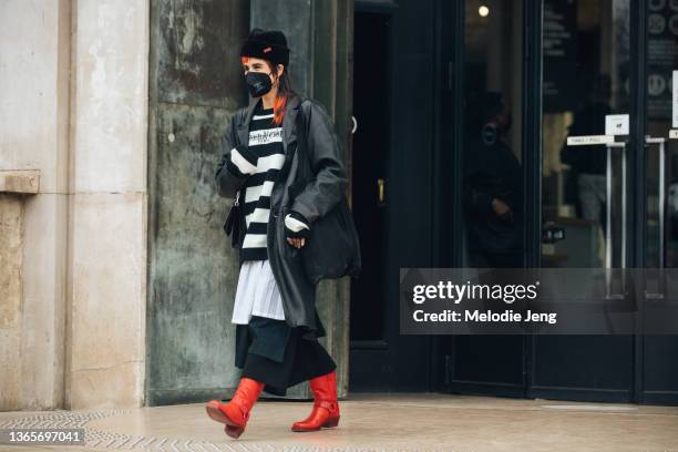 Photographer and Creative Director Eva Losada wears a black hat, black face mask, black leather jacket, Maison Margiela black and white striped...