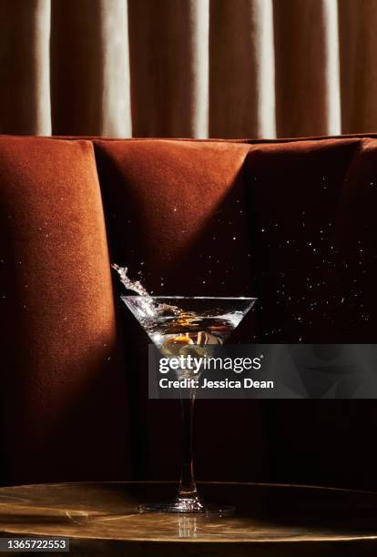 martini glass with splashing olives in swanky environment. - cocktail fotografías e imágenes de stock