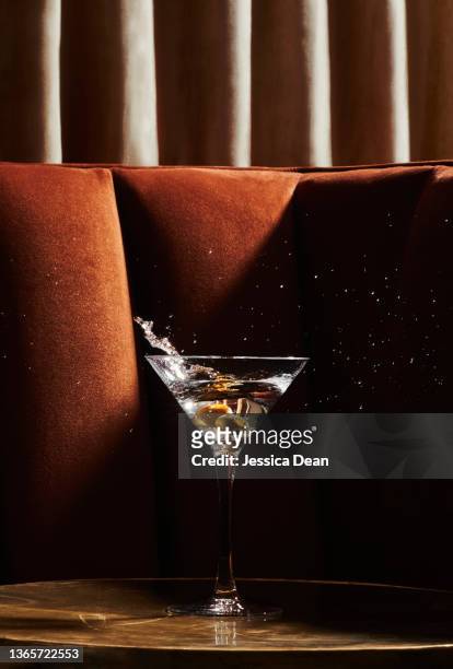 martini glass with splashing olives in swanky environment. - martini bildbanksfoton och bilder