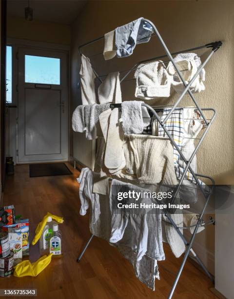 Hallway of a house during the Covid-19 lockdown, showing nappies and baby clothes on a drying rack, next to disinfectant and rubber gloves which are...