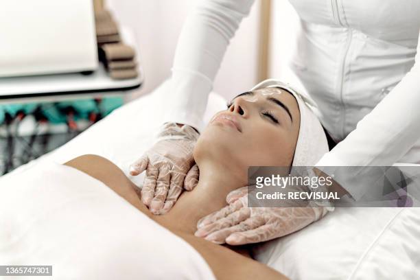 professional beautician doing facial and massage treatments to a woman at the spa - parte del cuerpo humano stock pictures, royalty-free photos & images