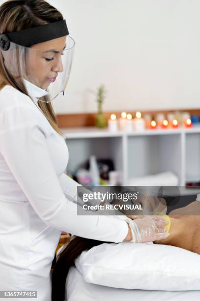 professional beautician doing facial and massage treatments to a woman at the spa - parte del cuerpo humano stock pictures, royalty-free photos & images