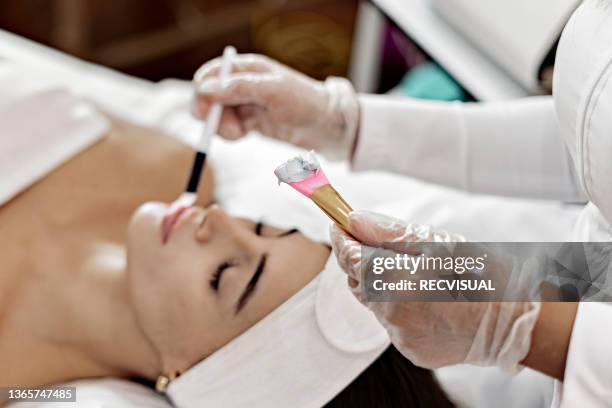 professional beautician applies white cosmetic cream to a girl lying on a massage table - parte del cuerpo humano stock pictures, royalty-free photos & images