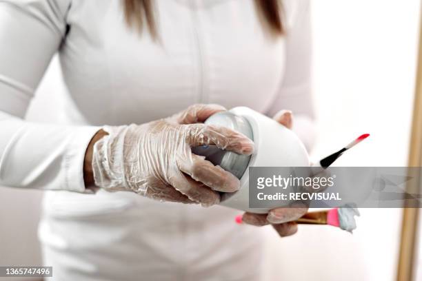 close-up of the hands of a professional beautician holding a cosmetic cream - parte del cuerpo humano stock pictures, royalty-free photos & images