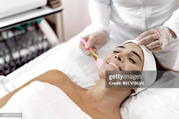 professional beautician applies cosmetic cream to a young woman lying on a massage table - parte del cuerpo humano stock pictures, royalty-free photos & images