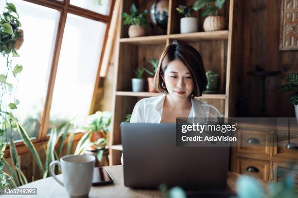 young asian woman managing online banking on laptop, taking care of her money and finances while relaxing at home. banking with technology - accounting stock pictures, royalty-free photos & images