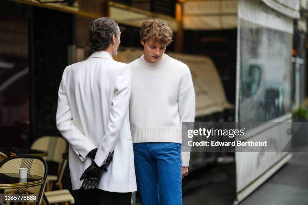 Guest wears a white blazer jacket, black leather gloves, black flared suit pants, a guest wears a white wool pullover, high waist blue denim flared...