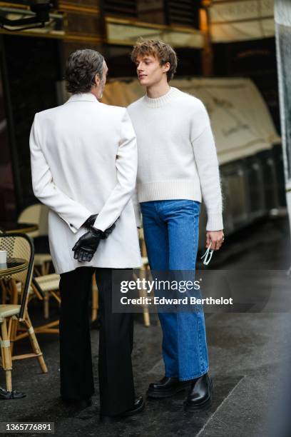 Guest wears a white blazer jacket, black leather gloves, black flared suit pants, black shiny leather shoes, a guest wears a white wool pullover,...