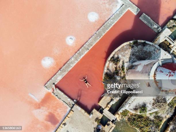a woman is lying down in a pink water of a salt flat to have a wellness treatment - salt flat 個照片及圖片檔