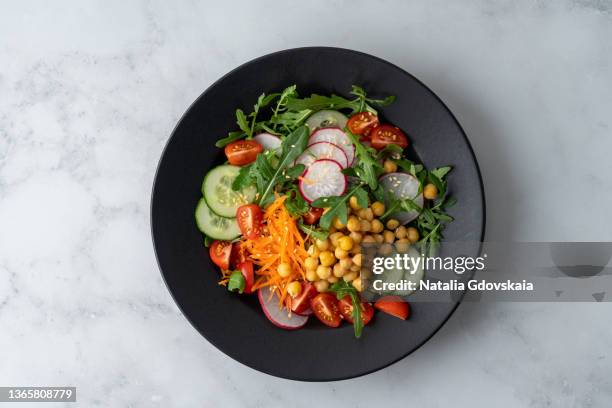 top view of vegetarian fresh salad with tomatoes, cucumbers, carrots, redishes, aragula, chickpeas - cucumber leaves fotografías e imágenes de stock