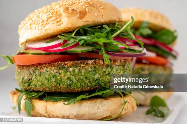 closeup of vegetarian plant based burgers with veggie patty and sliced vegetables. fresh vegan snack - burgers stock-fotos und bilder