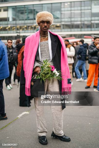 Guest wears a beige fur hat, gold earrings, gold and silver chain necklaces, a neon pink wool large fringed scarf, a gray mesh wool t-shirt, a white...