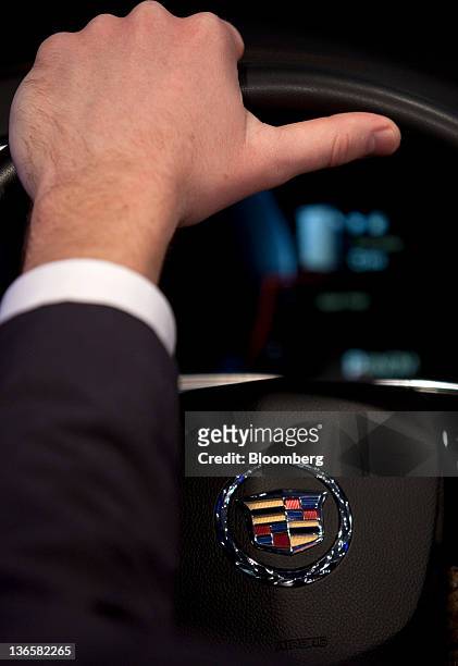 An attendee grips the steering wheel of the General Motors Co. Cadillac User Experience Infotainment model during the unveiling of the 2013 Cadillac...