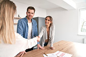 Handshake of real estate agent and young caucasian couple