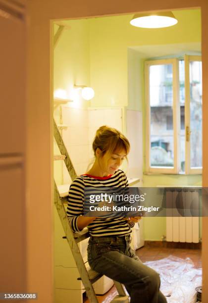woman taking a break after paint job, reading messages on mobile phone - new hairstyle stock pictures, royalty-free photos & images