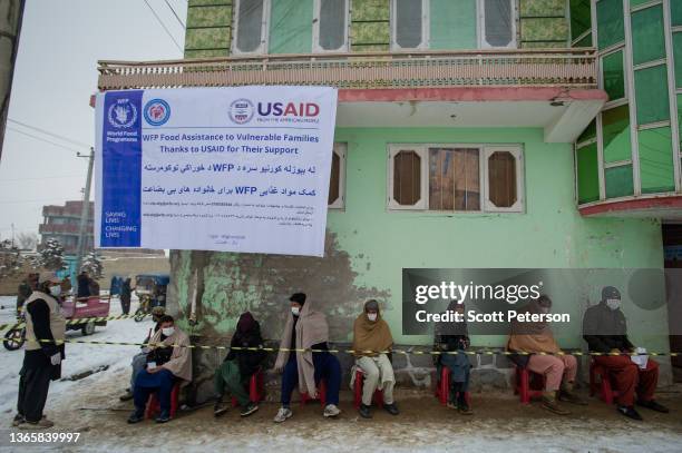 Afghan men wearing masks to prevent the spread of Covid-19 line up as the UN World Food Program distributes a critical monthly food ration, with food...