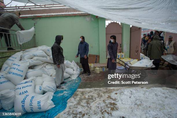 Afghan workers prepare sacks of flour, as the UN World Food Program distributes a critical monthly food ration, with food largely supplied by the US...