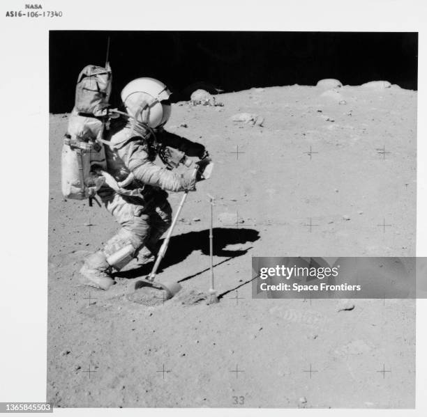 American NASA astronaut John W Young using the lunar surface rake and a set of tongs to collect lunar samples near the North Ray crater during the...
