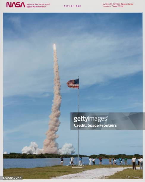 Spectators watch as the Space Shuttle Challenger leaving a plume of smoke at the launch of mission STS-51-F launch from Kennedy Space Center on...