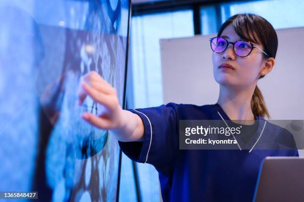 young female doctor giving a speech or presentation to colleagues - doctor presentation stock pictures, royalty-free photos & images