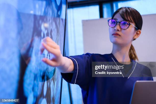 young female doctor giving a speech or presentation to colleagues - exame médico procedimento médico imagens e fotografias de stock