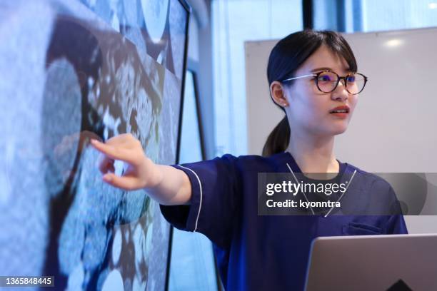 young female doctor giving a speech or presentation to colleagues - doctor presentation stock pictures, royalty-free photos & images