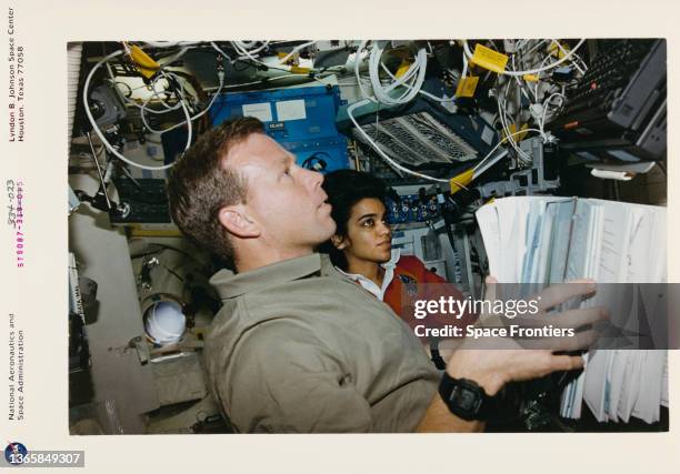 American NASA astronaut Steven W Lindsey and Indian NASA astronaut Kalpana Chawla monitor an experiment in the mid-deck glovebox of the Space Shuttle...