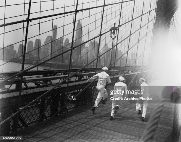 Actors Jules Munshin, Frank Sinatra and Gene Kelly dressed as sailors on Brooklyn Bridge in New York City, USA, to publicise the musical film 'On The...