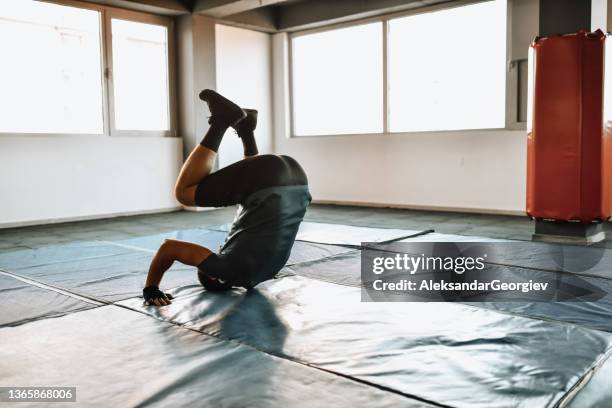 athletic male performing forward roll exercise in gym - somersault stock pictures, royalty-free photos & images