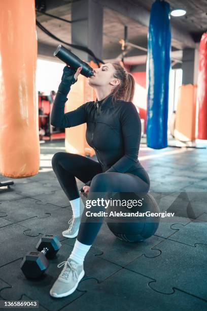 water break time for female athlete sitting on fitness ball in gym - white shoelace stock pictures, royalty-free photos & images