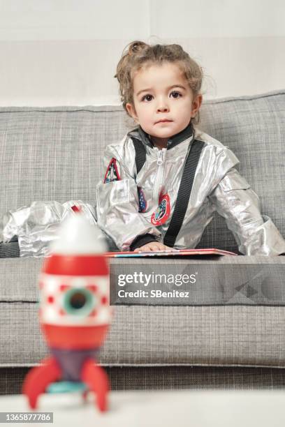 little astronaut is lying on the sofa - rocket book stock pictures, royalty-free photos & images