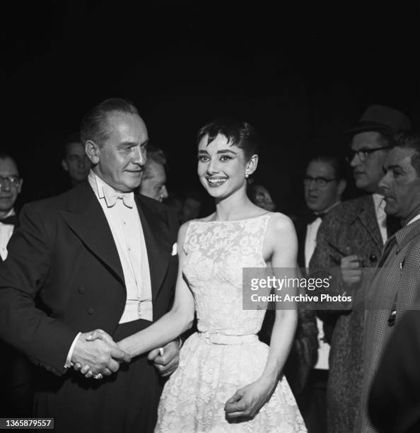 Actress Audrey Hepburn shakes hands with actor Fredric March , who is co-hosting the awards, at the 26th Academy Awards at the NBC Century Theatre in...