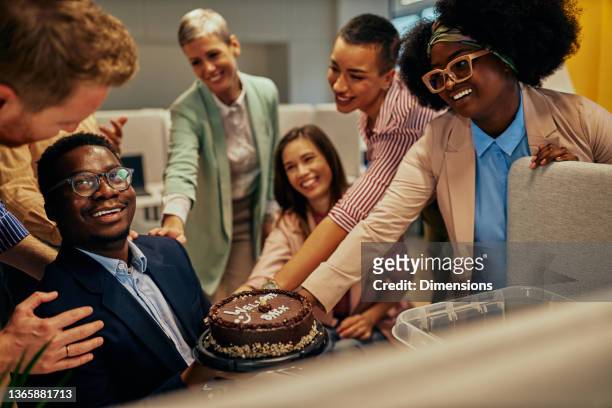 people congratulating their colleague return to work with welcome back-cake - office party stock pictures, royalty-free photos & images